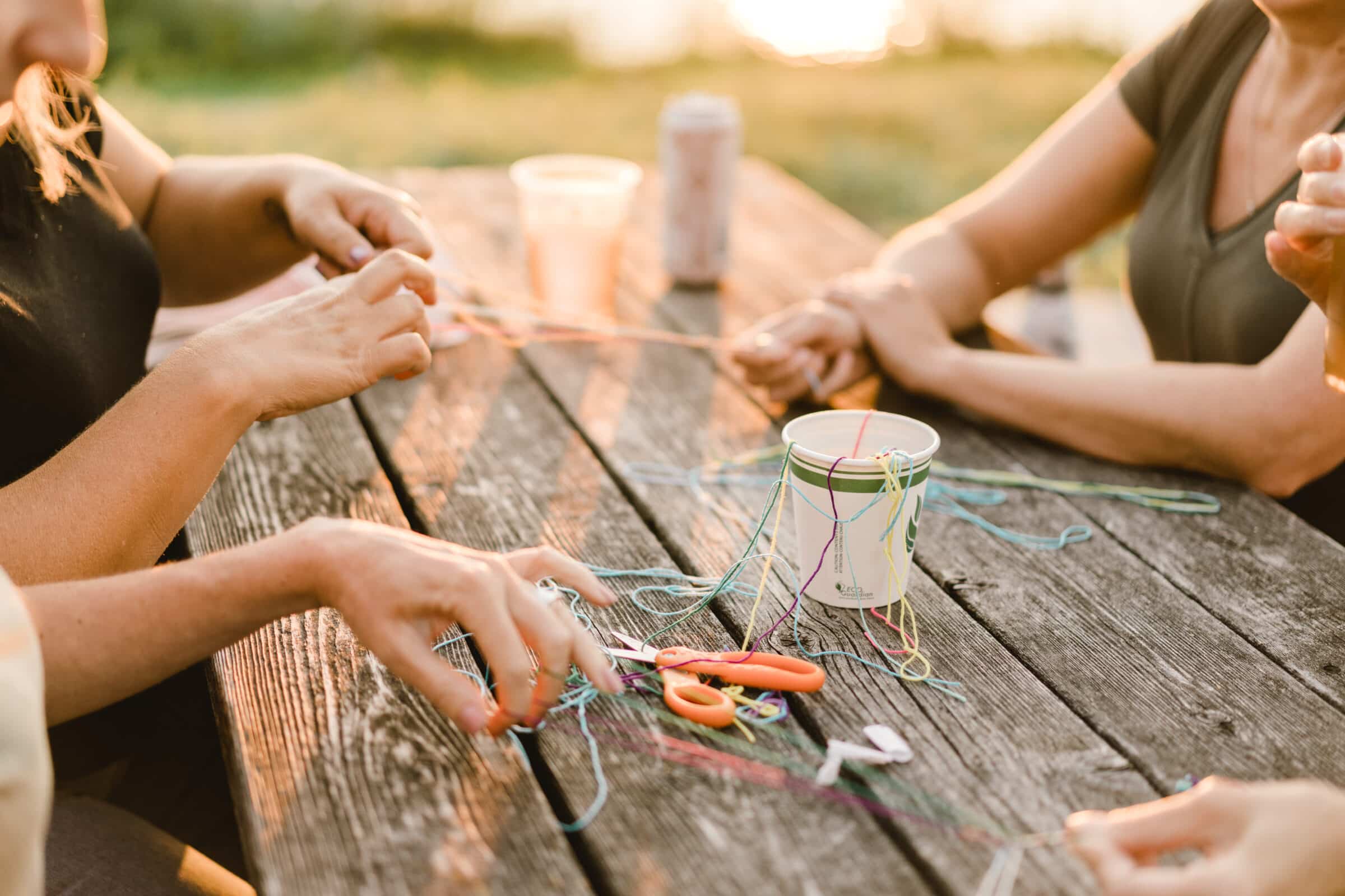 hands braiding friendship bracelets over table