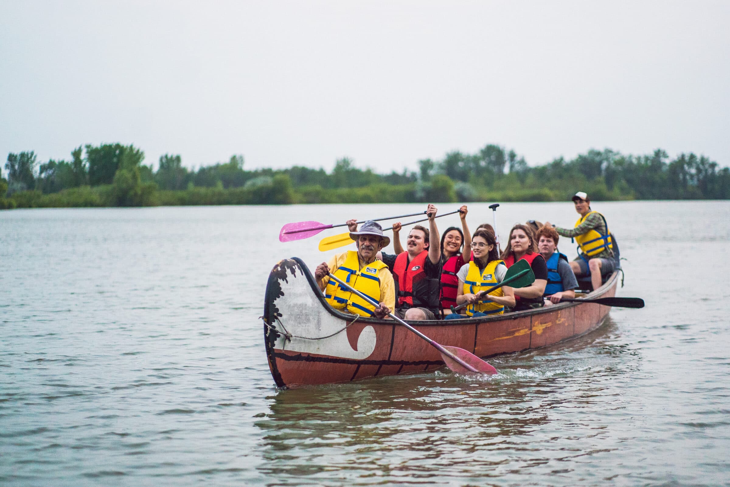 voyageur canoe of people paddling across lake