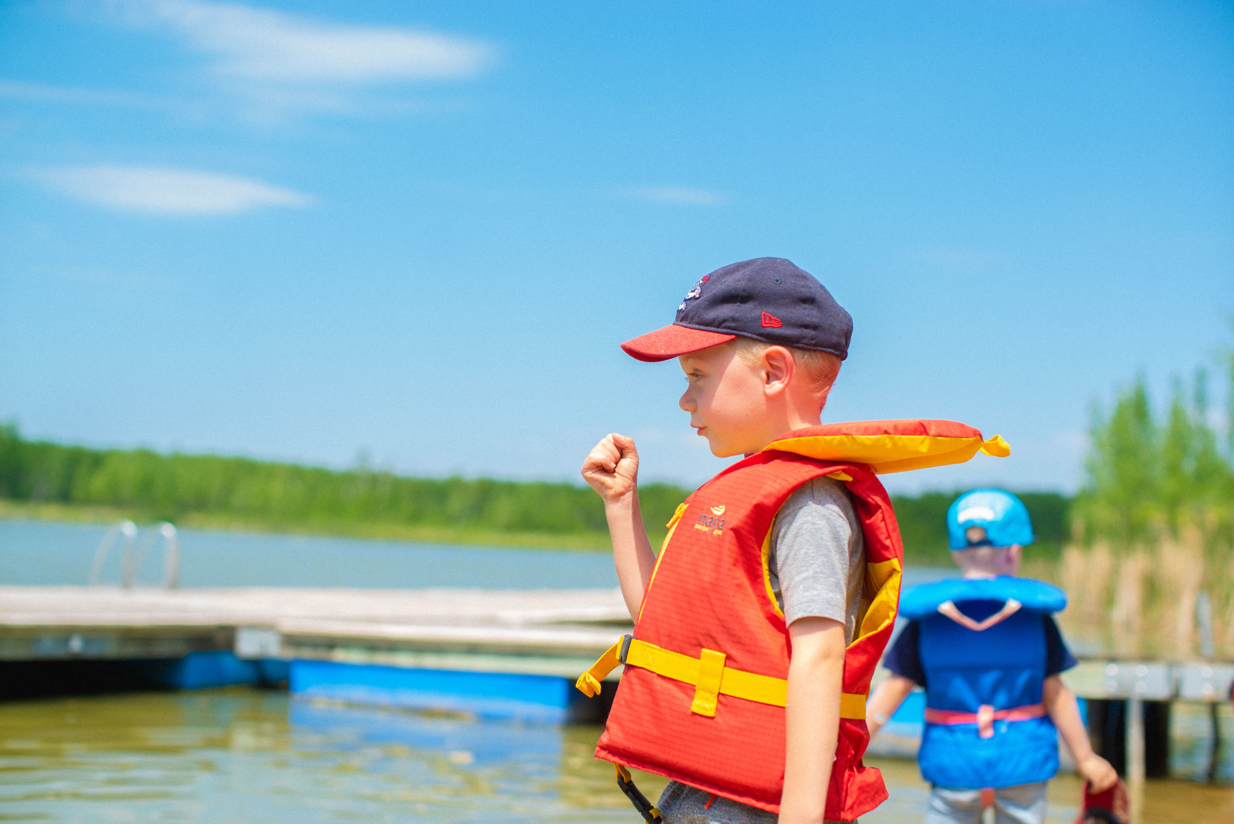 Young camper in a lifejacket looking out into water.