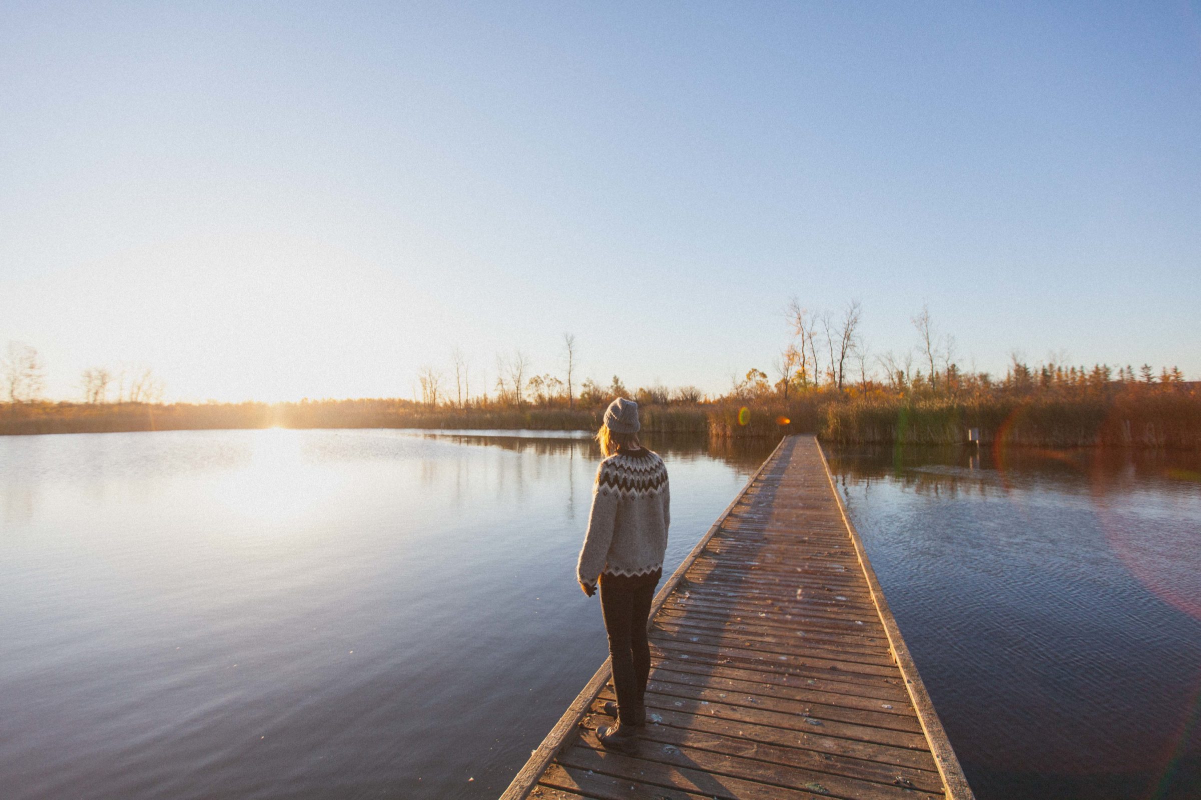 Visitor standing on boardwalk overlooking lake.