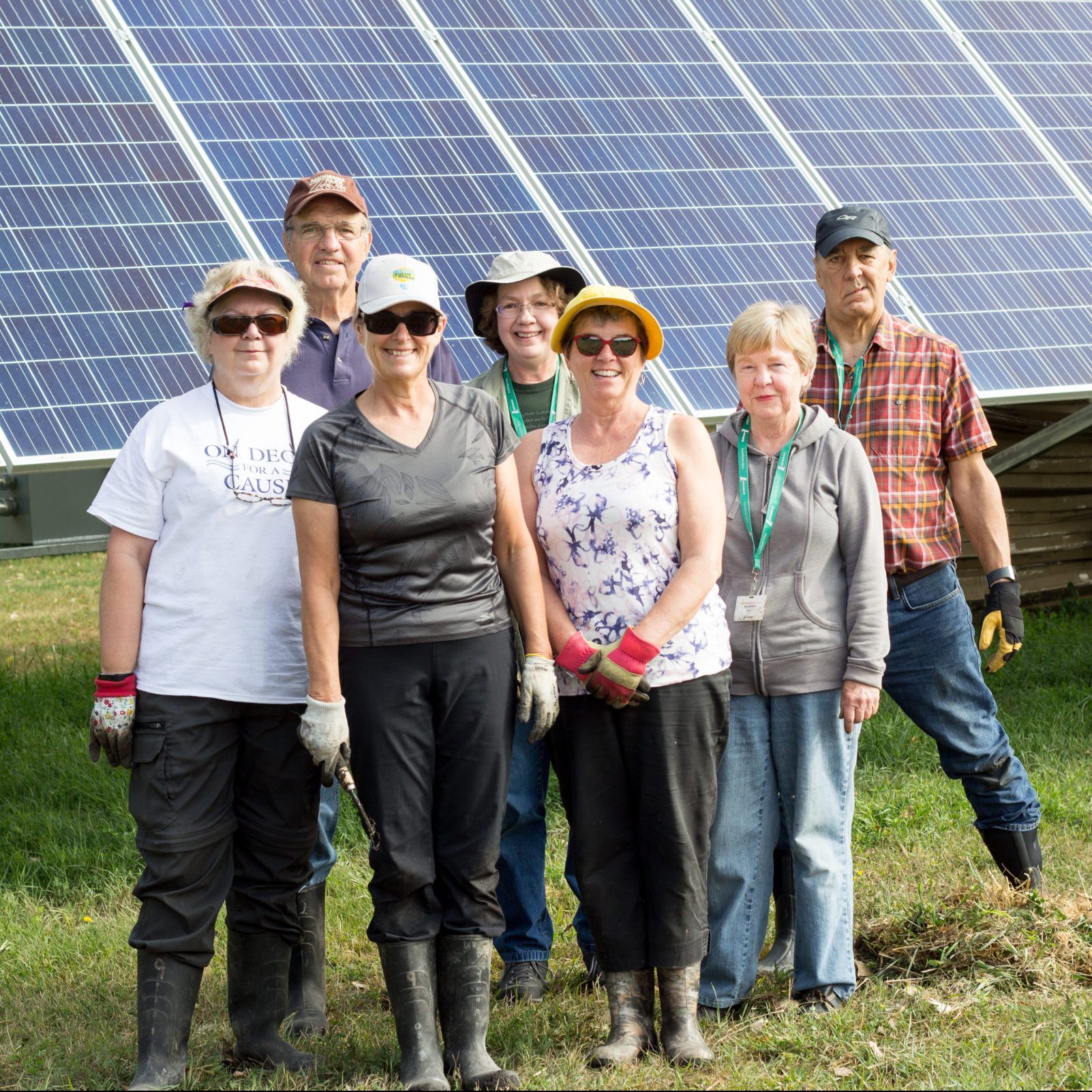 Group of volunteers standing in front of solar panels.