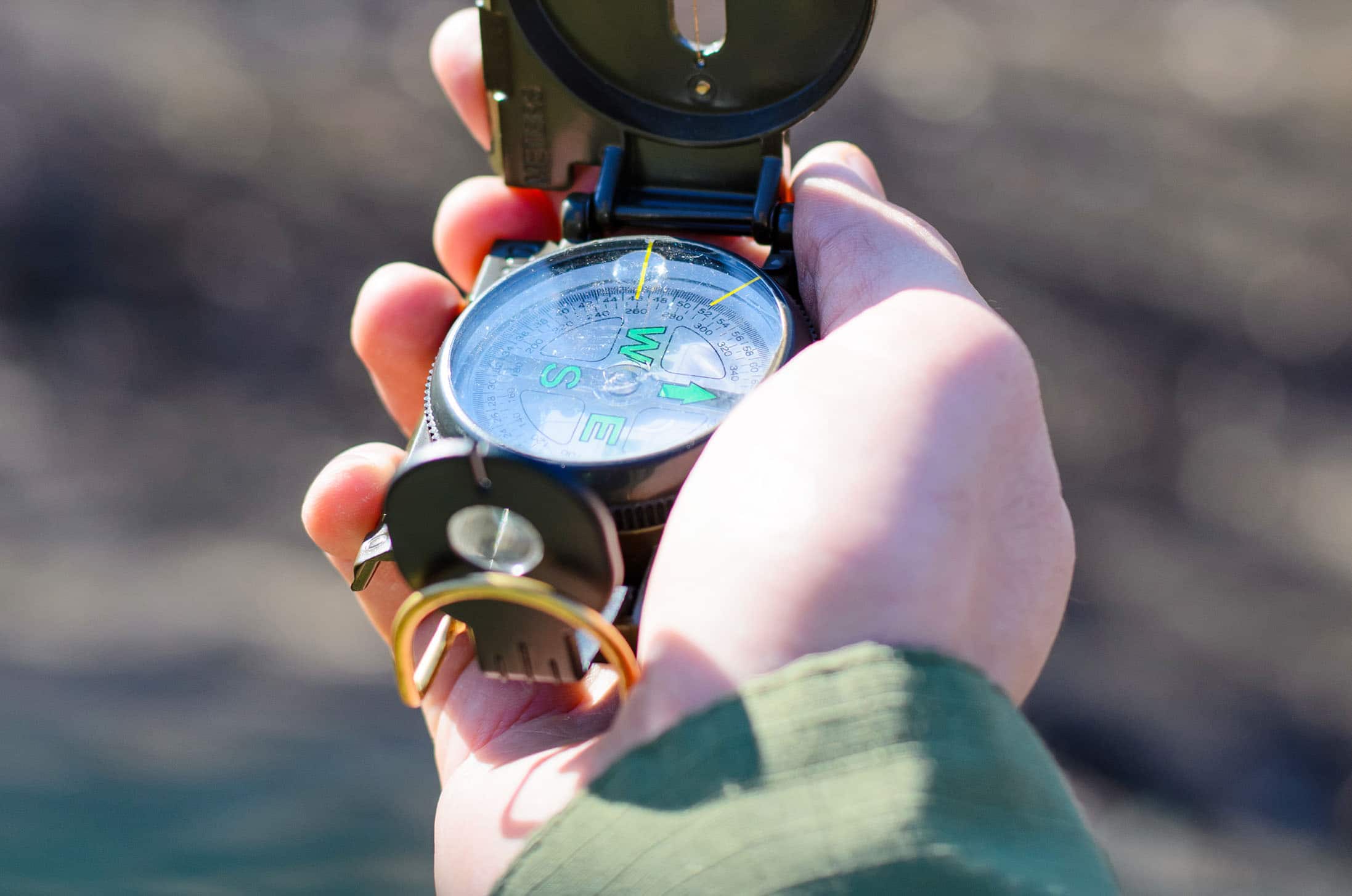A hand holds out a compass.