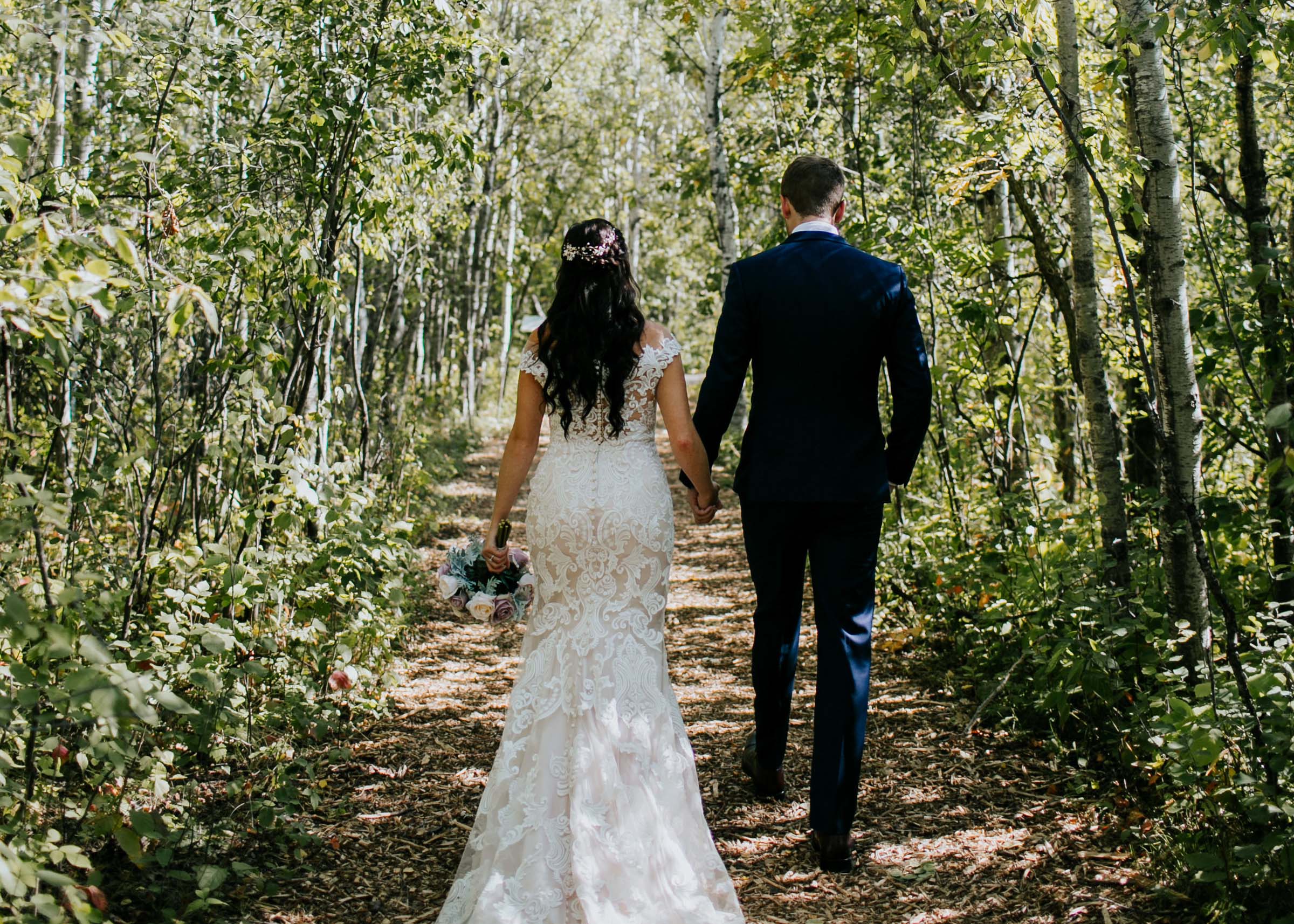 Newly married couple walk through the forest at FortWhyte Alive.