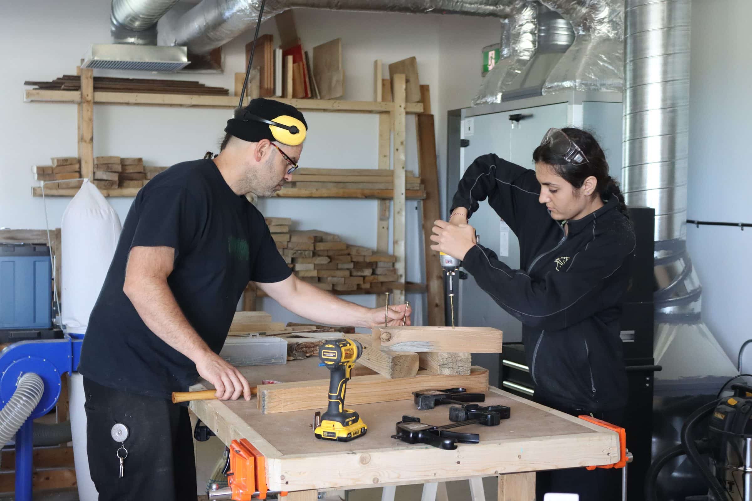 Patrick and a farm youth using drill in woodshed.