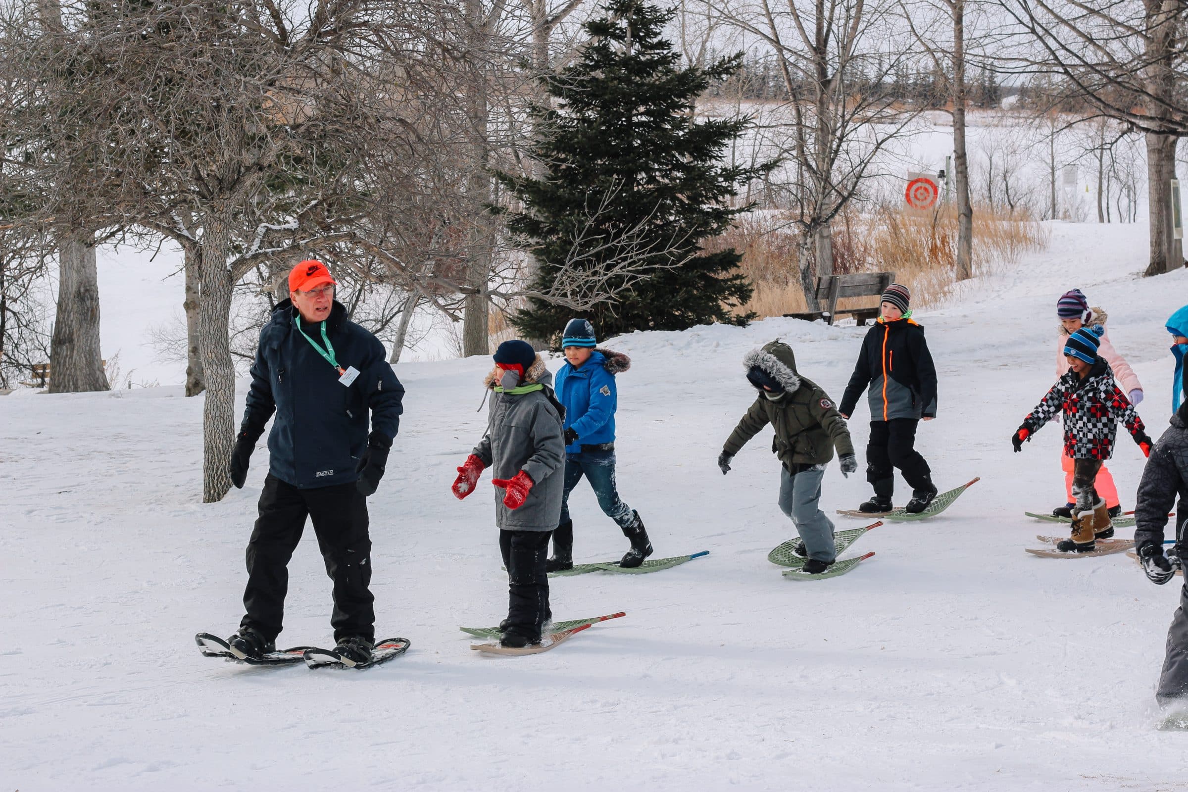 Volunteer leads school group snowshoeing.