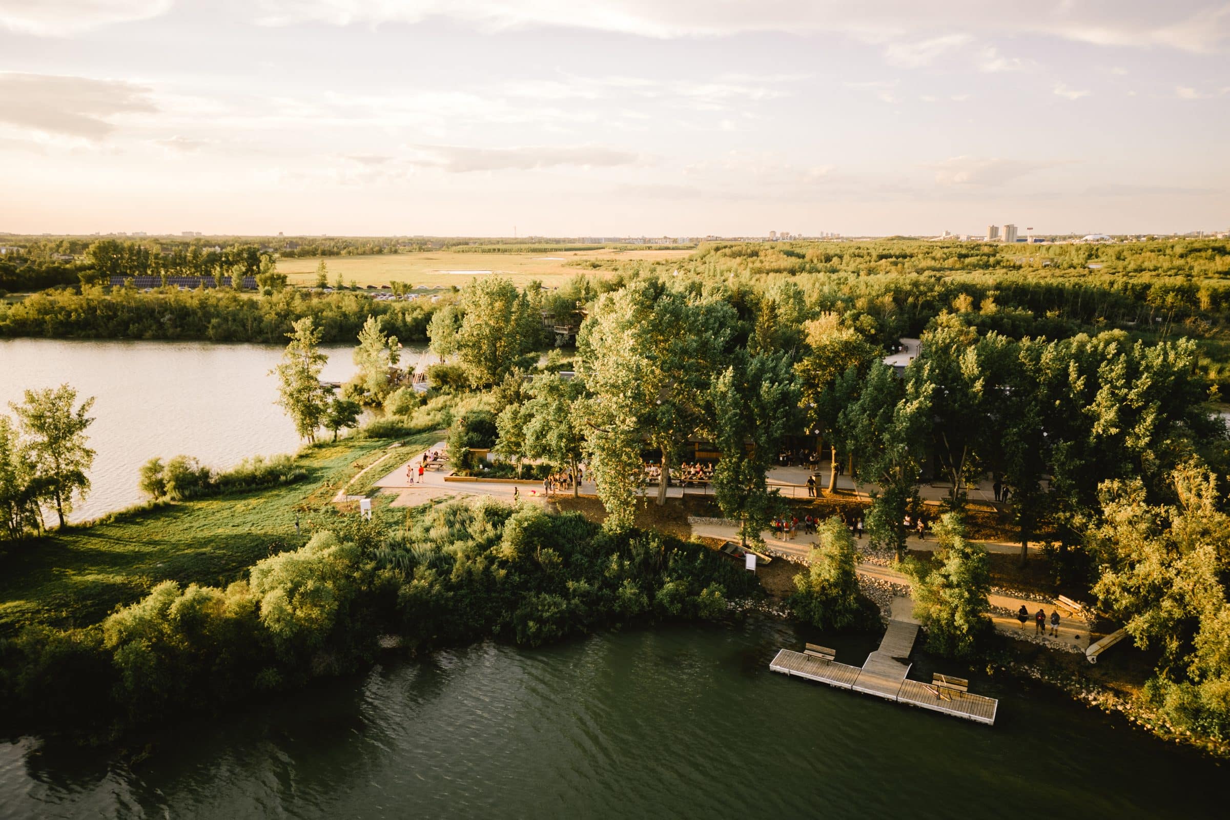 Aerial shot of FortWhyte lakes surrounding back patio and dock of the interpretive centre as seen peeking through the trees.