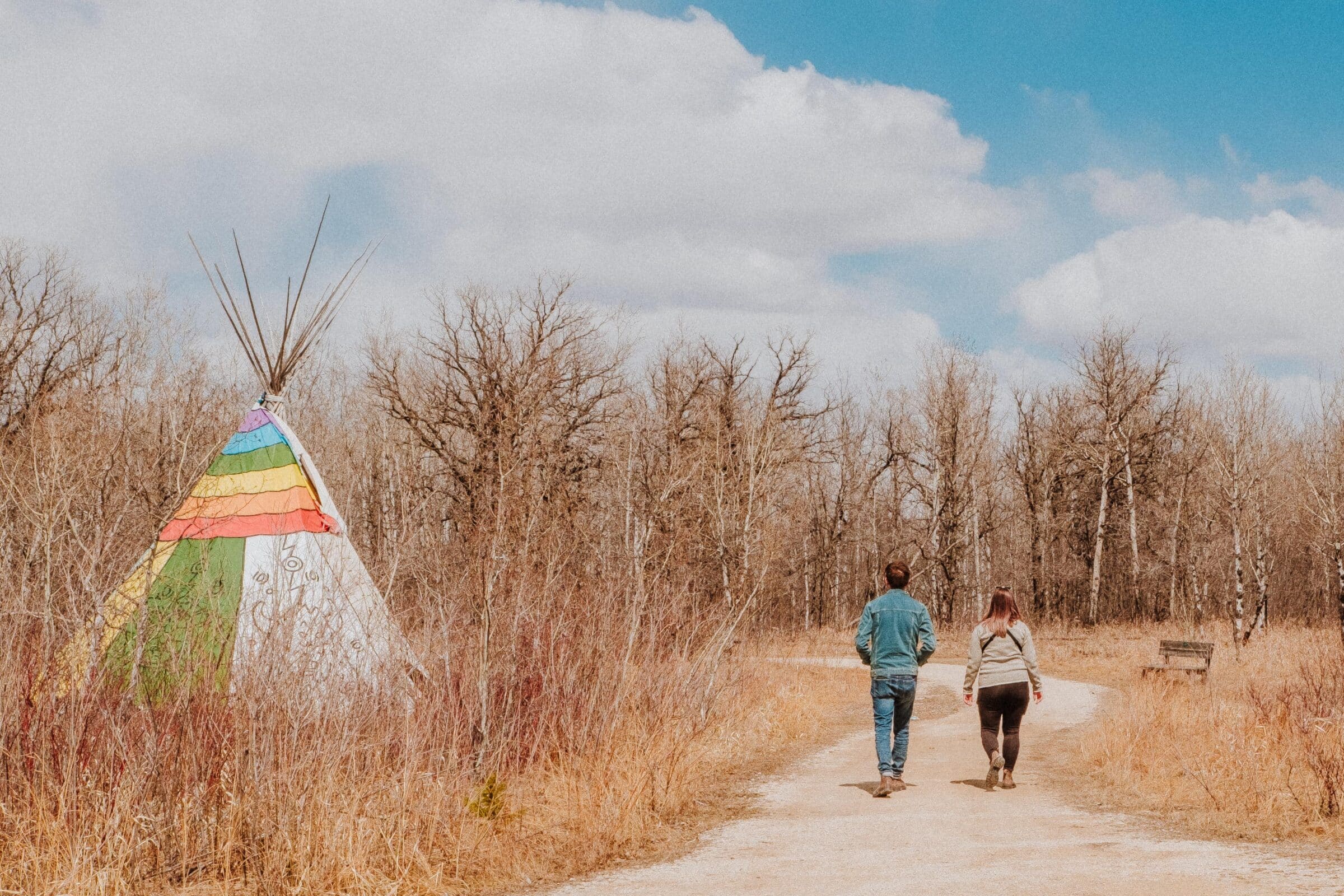 People walking on trail past colourful tipi in spring.