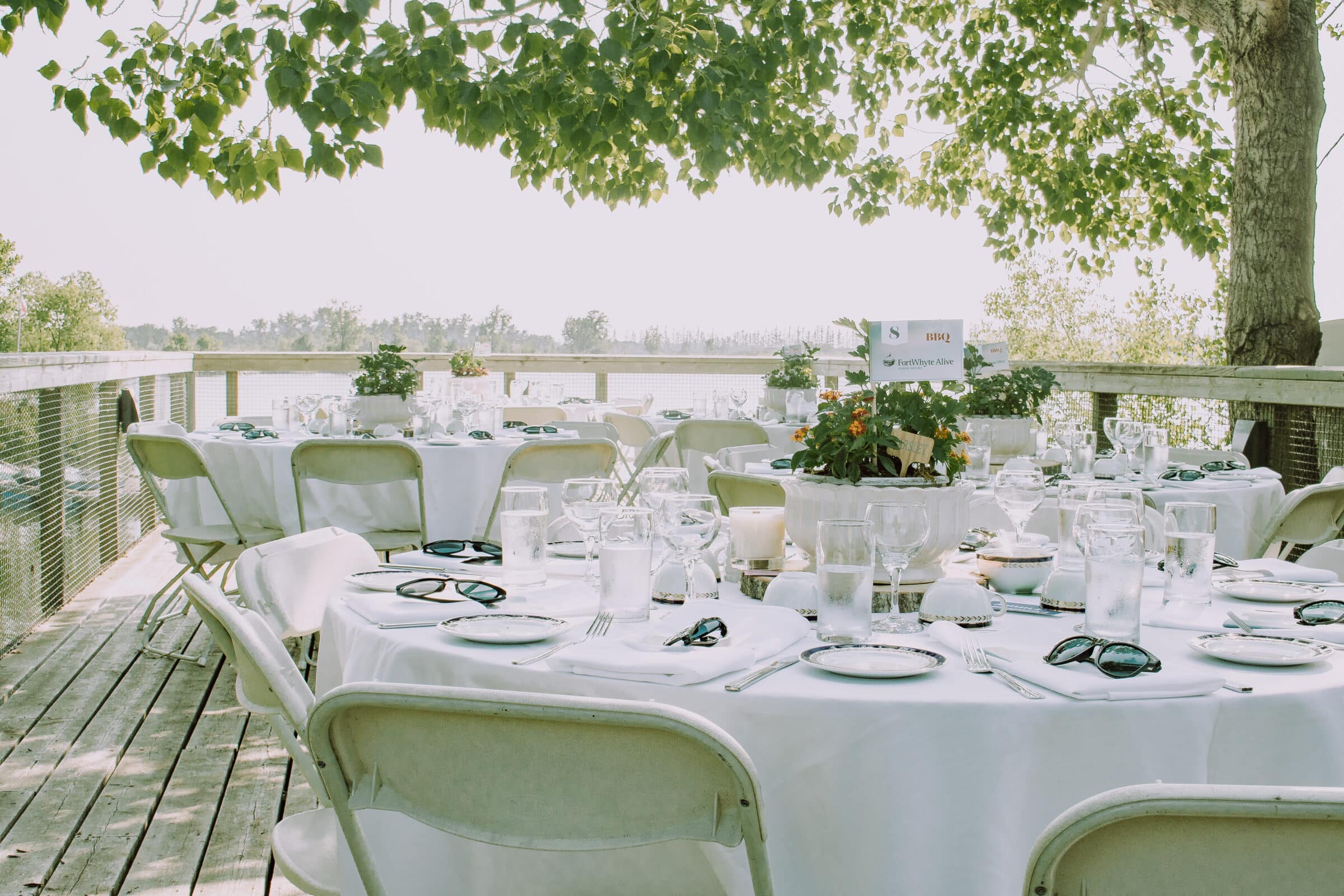 Tables on patio set with place settings on white tablecloth