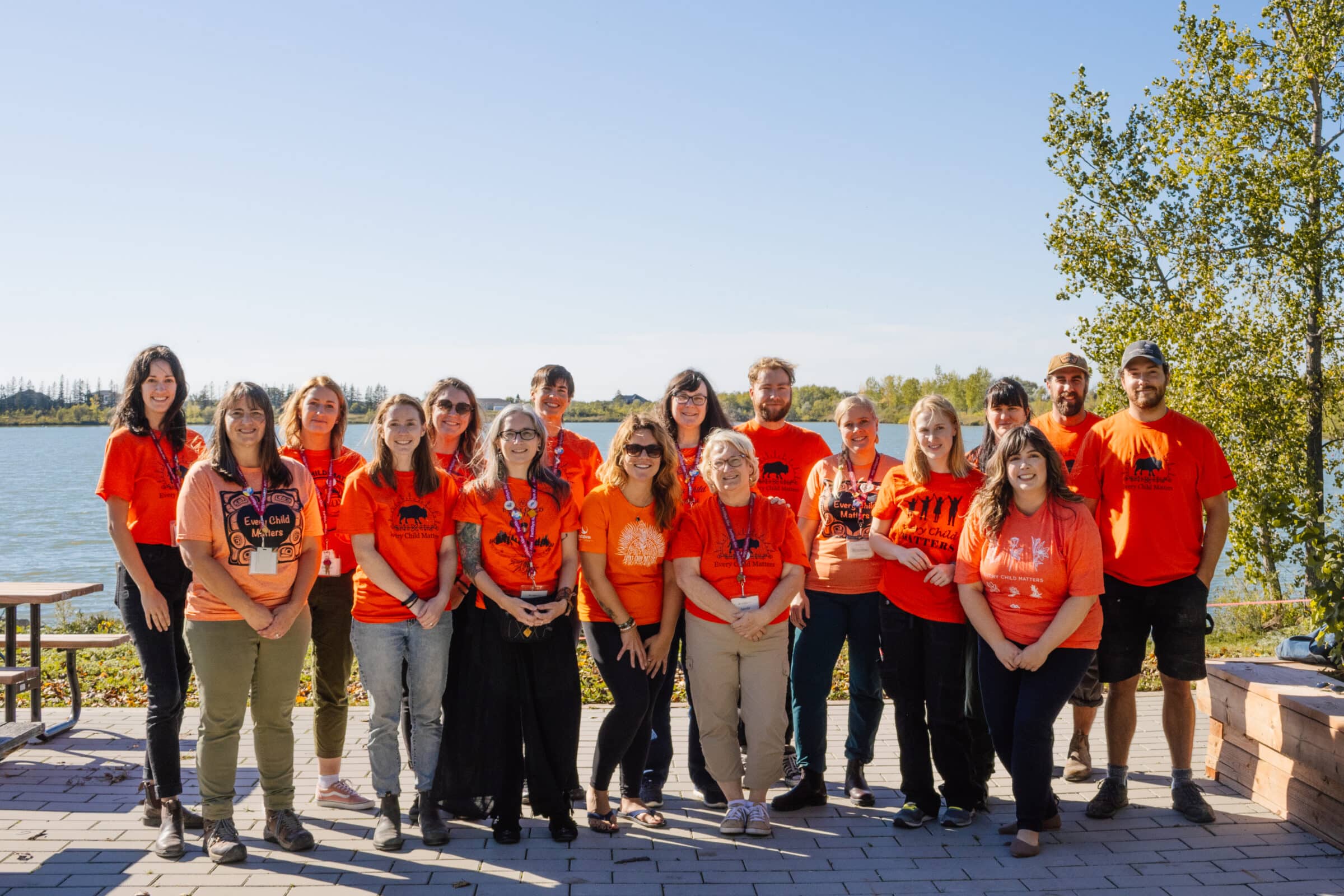 FortWhyte Alive staff in orange shirts stand lakeside