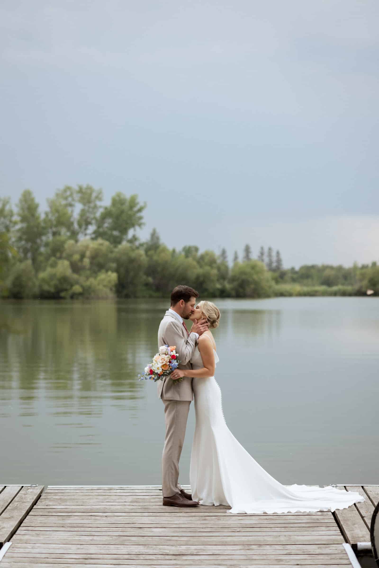 Bride and groom kiss lakeside